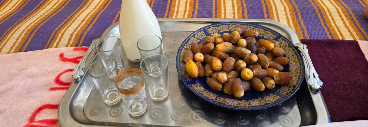 Plateau de dattes, verres et carafe de lait sur un tapis rayé